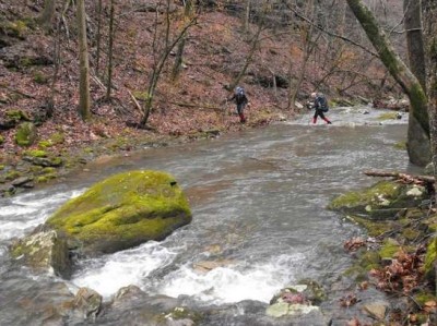 Two hikers carefully cross Bear Creek during a recent hike in the Ozark National Forest.